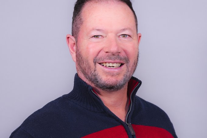 Deacon Bobby Ehnow smiling at the camera against a plain gray background.