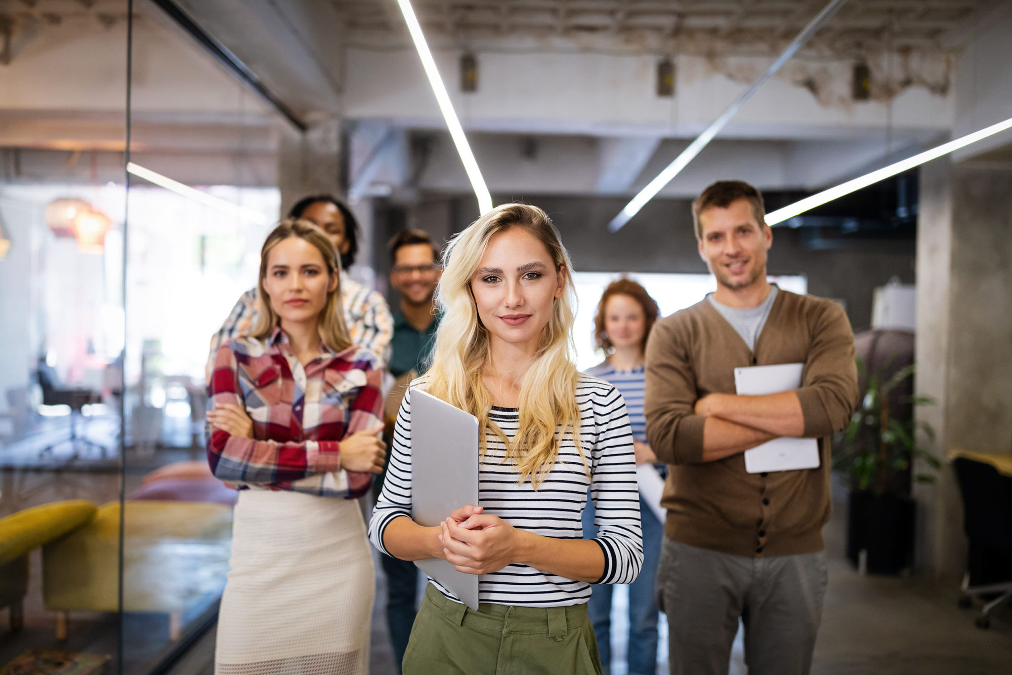 Younger men and women standing together looking towards the viewer.