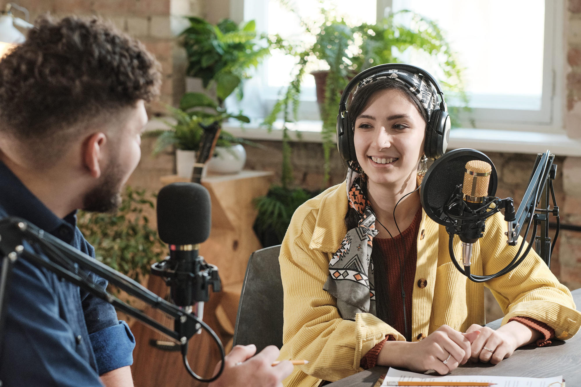 Young man and woman in front of microphones creating a podcast.